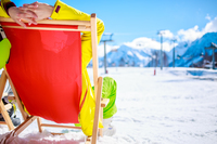 Ski-Sportler liegt in roter Sonnenliege vor Bergkulisse